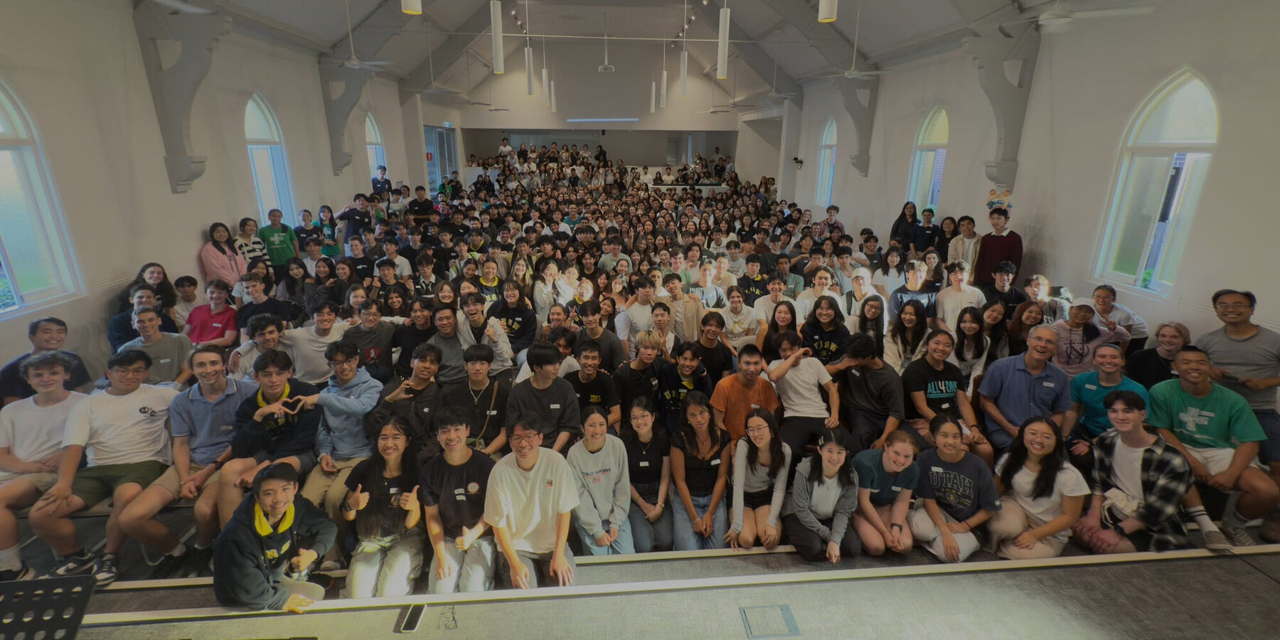 The Connect Sydney crowd packed into a church hall, waving at the camera