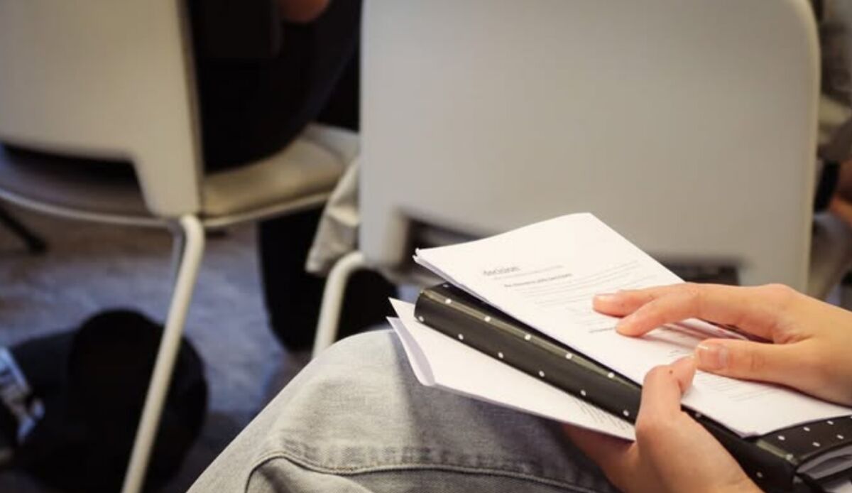 A grad holding printed talk notes on their lap during a session